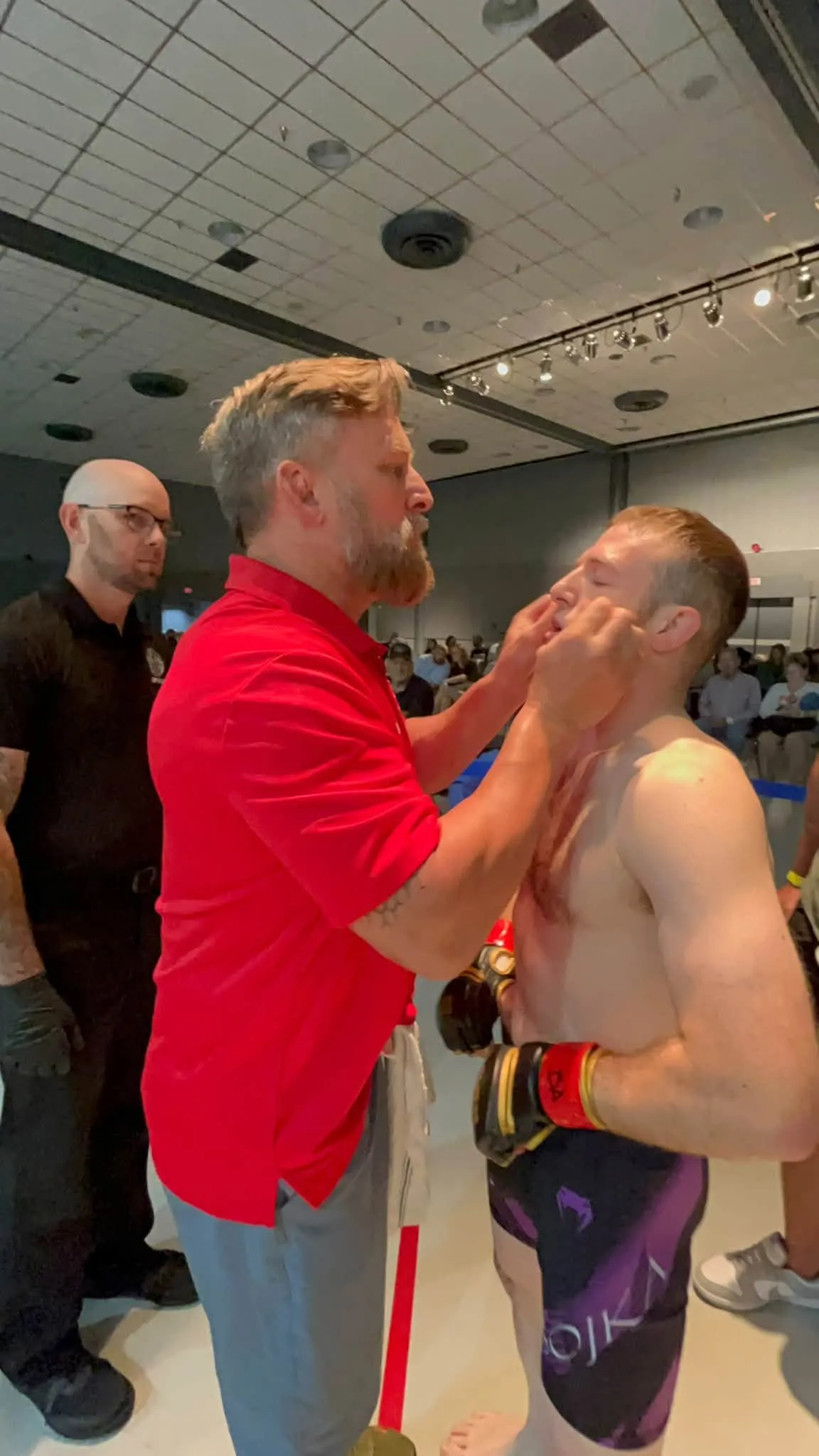 Coach Brent Mason, in a red polo, working on his fighter cageside on fight night